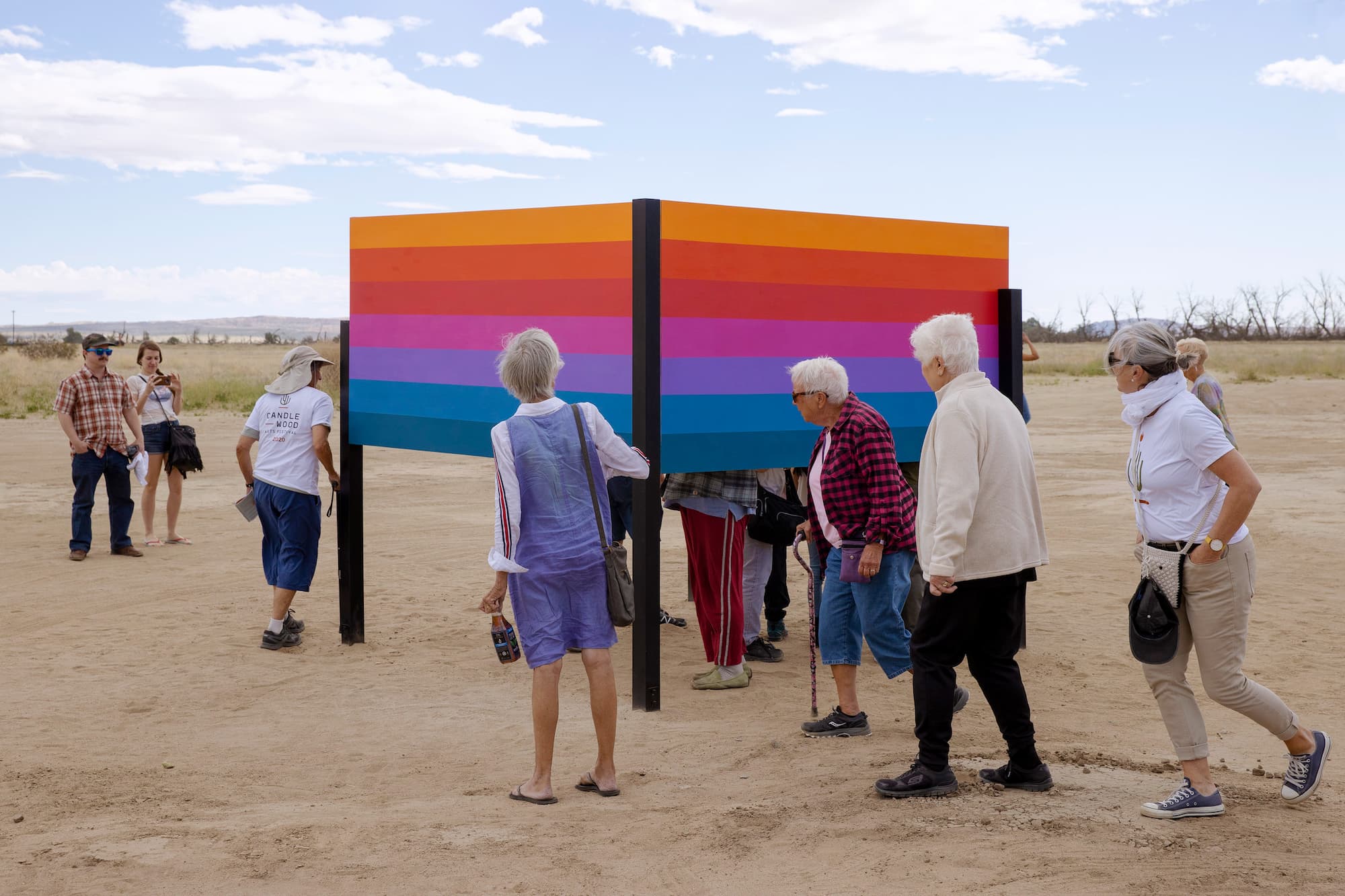 Rainbow sculpture in the desert with people exploring