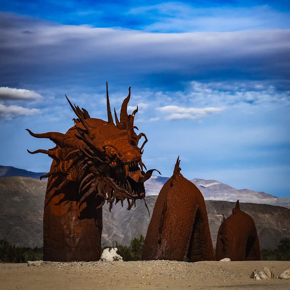Snake sculpture under a dramatic blue sky